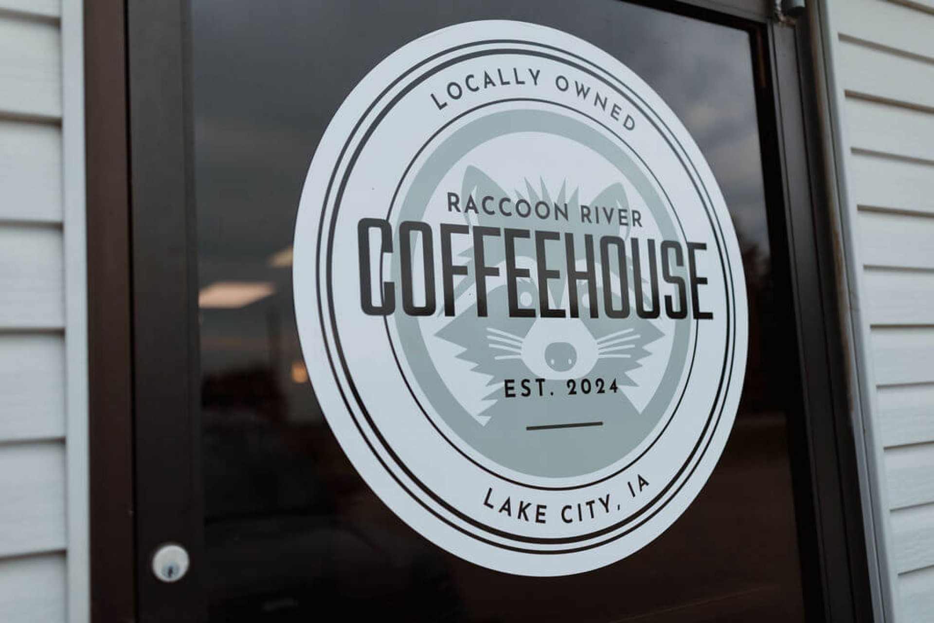 Locally owned Raccoon River Coffeehouse est. 2024 Lake City, Iowa sign on the door to the coffeehouse.